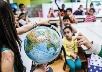 Teacher shows globe to children.