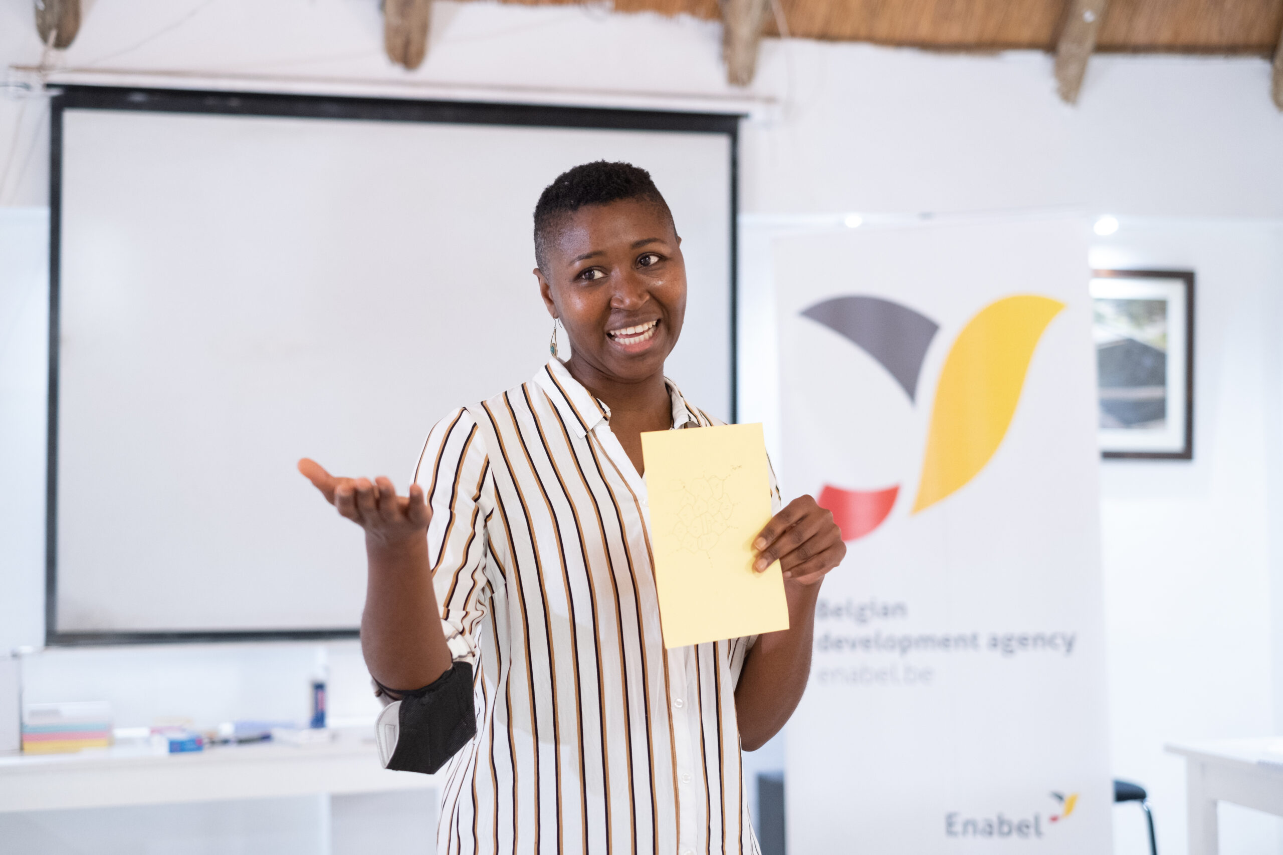 Women presenting and smiling. Enabel logo behind her.